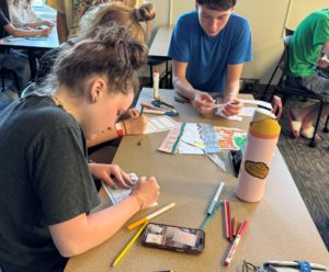 A small group of JBA students coloring and crafting at a table.
